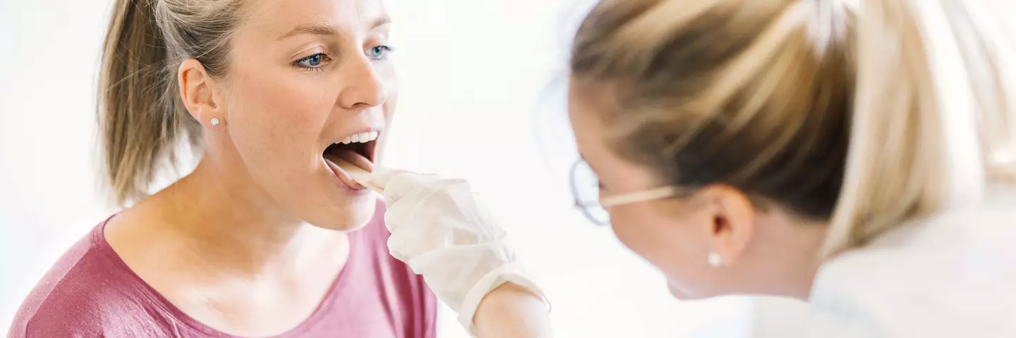 Une médecin examine la gorge d’une patiente 