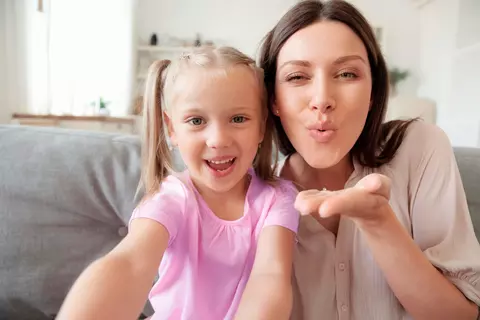 Mädchen und Frau sitzen fröhlich auf Sofa