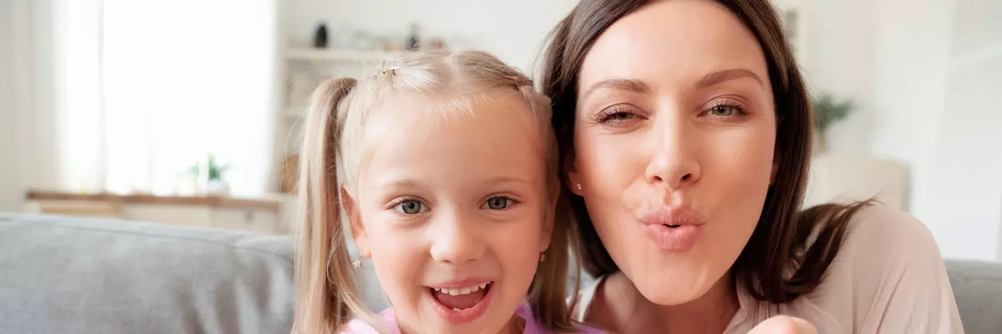 Mädchen und Frau sitzen fröhlich auf Sofa
