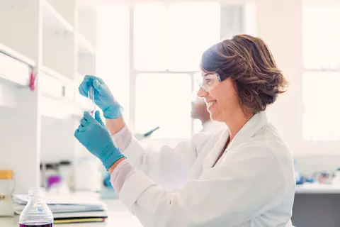 Frau im Labor mit Handschuhen und Schutzbrille 