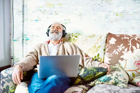 Älterer Herr hört auf dem Sofa Musik 