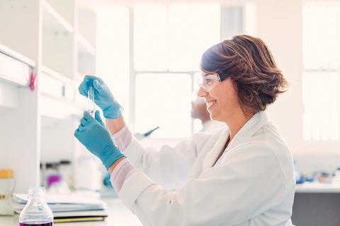 Frau im Labor mit Handschuhen und Schutzbrille