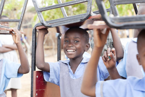 Schulkind in Afrika mit Stuhl auf dem Kopf 