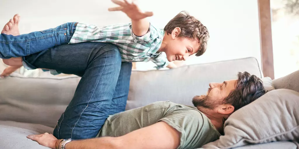 Un père et son fils jouent sur le canapé